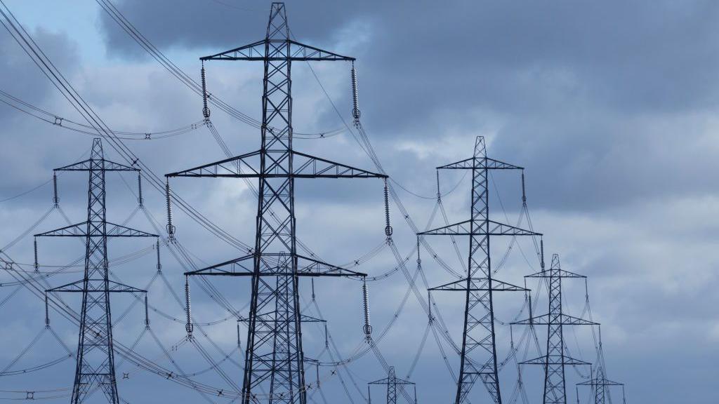 Several electricity pylons stand tall above English farmland