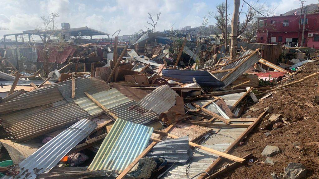 Piles of sheet metal and wooden slats lie on the ground in Mayotte