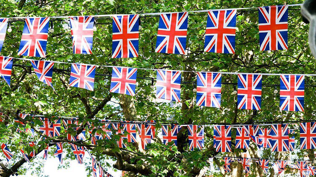 Bunting hanging up across trees outside.