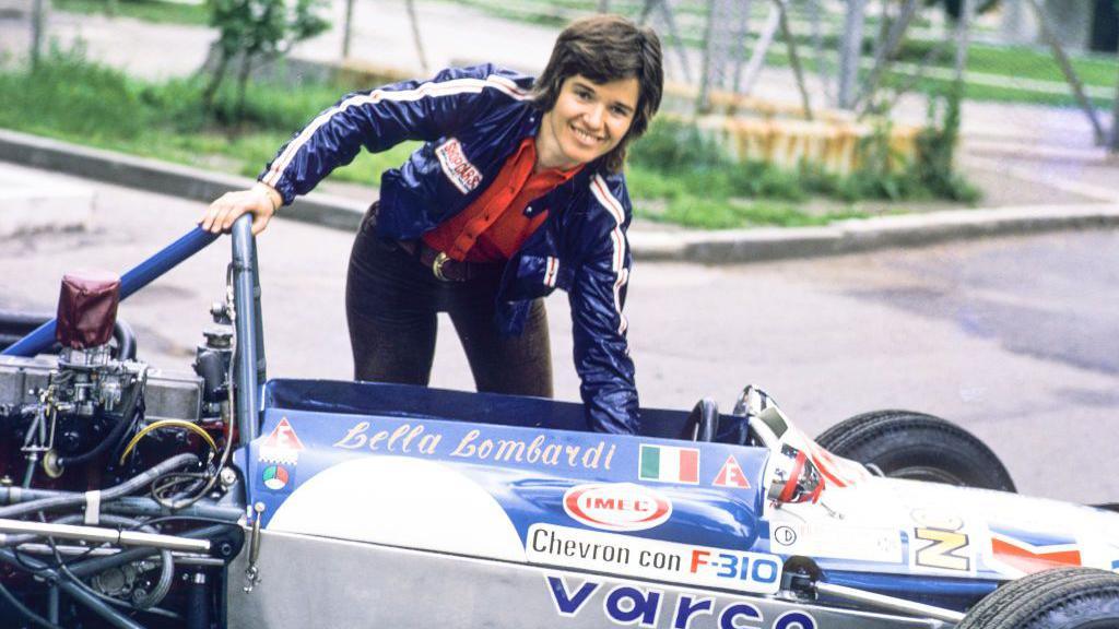 Lella Lombardi stands next to a car in the 1970s 