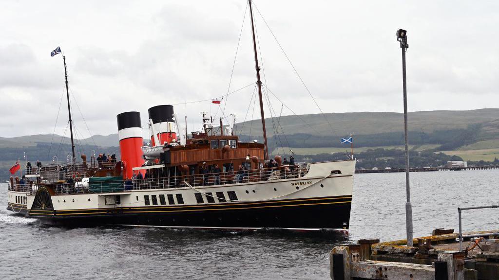 the paddle steamer in the water as it approaches a pier