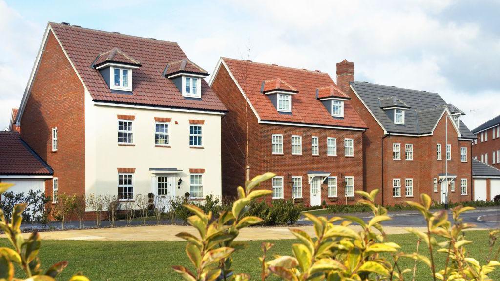 A row of newly-build houses in front of a lawn.