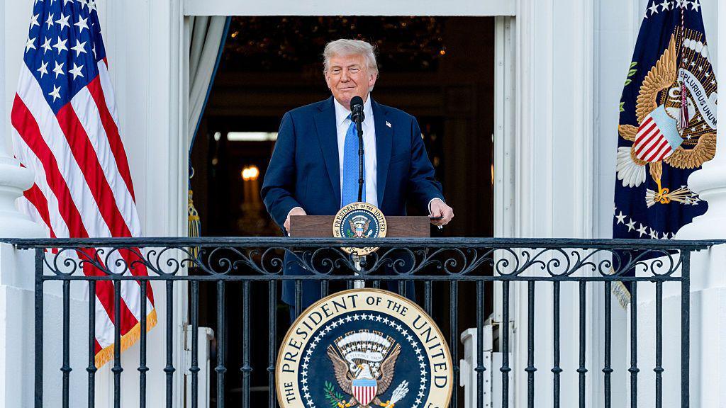 Donald Trump standing on the balcony in the White House.