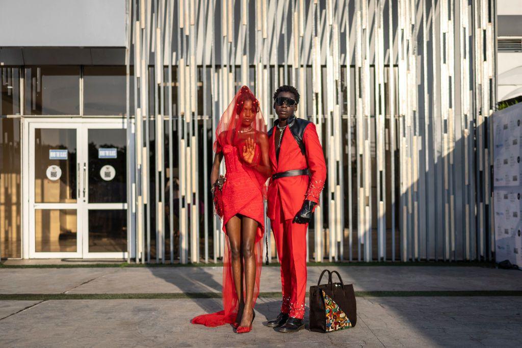 A man and a woman dressed in red and black pose for a photograph as they arrive at the Federal Palace Hotel for Lagos Fashion Week on 26 October.