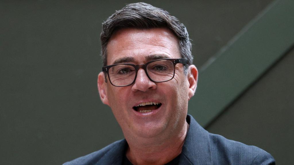 Andy Burnham smiles while giving a speech