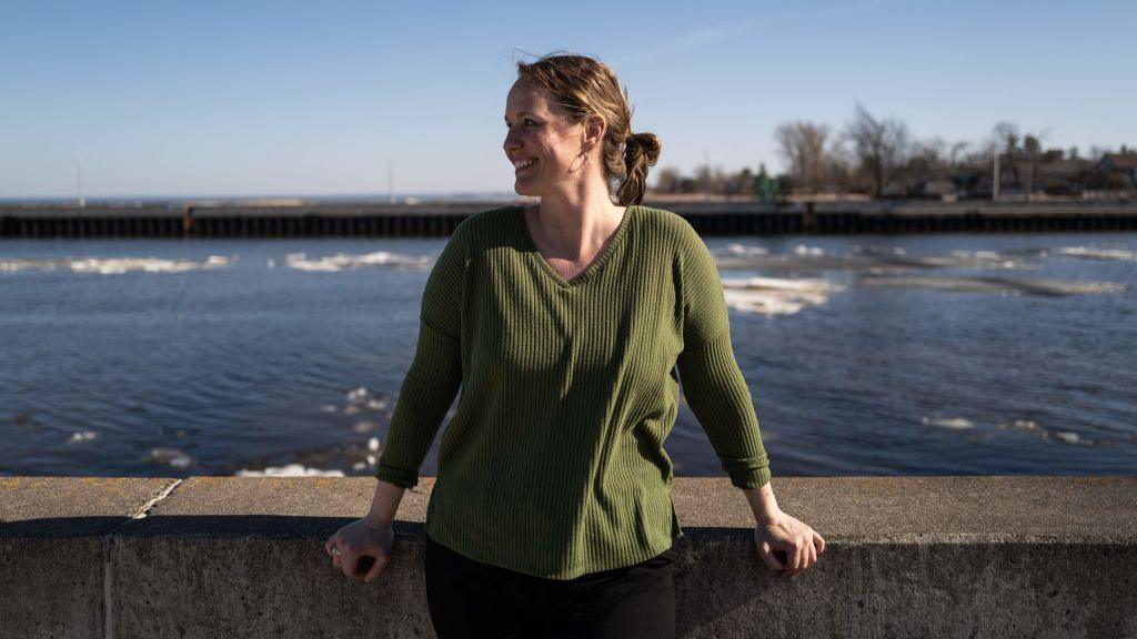 Christina Welch wears a green sweater while standing near the water in Duluth