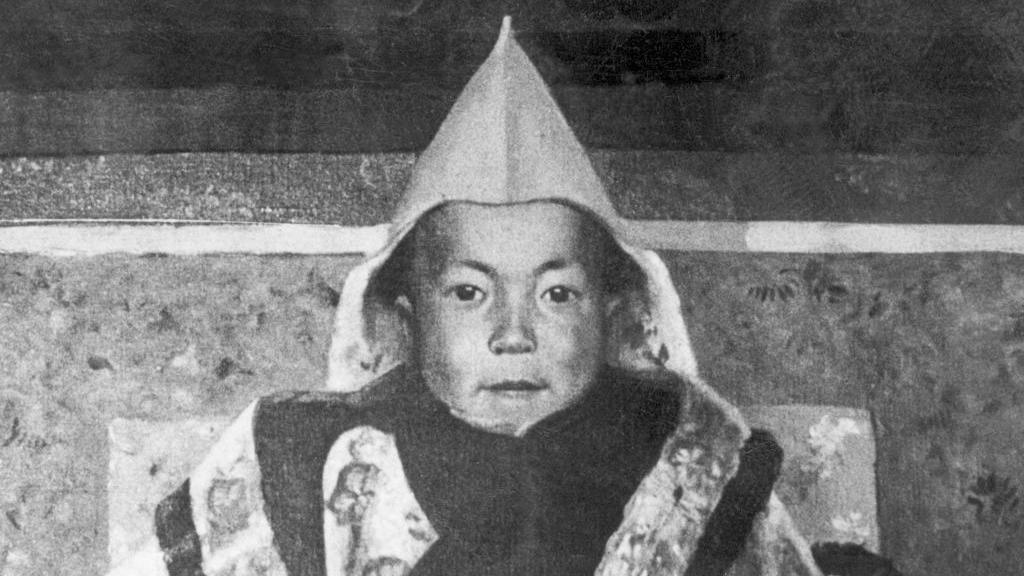 Black-and-white painting of the Dalai Lama as a toddler, wearing a conical hat. 