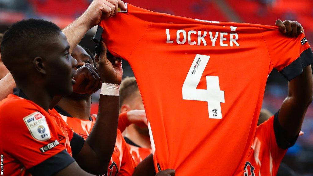 Luton Town players hold a Tom Lockyer shirt in support of their captain after the Wembley play-off final triumph against Coventry City