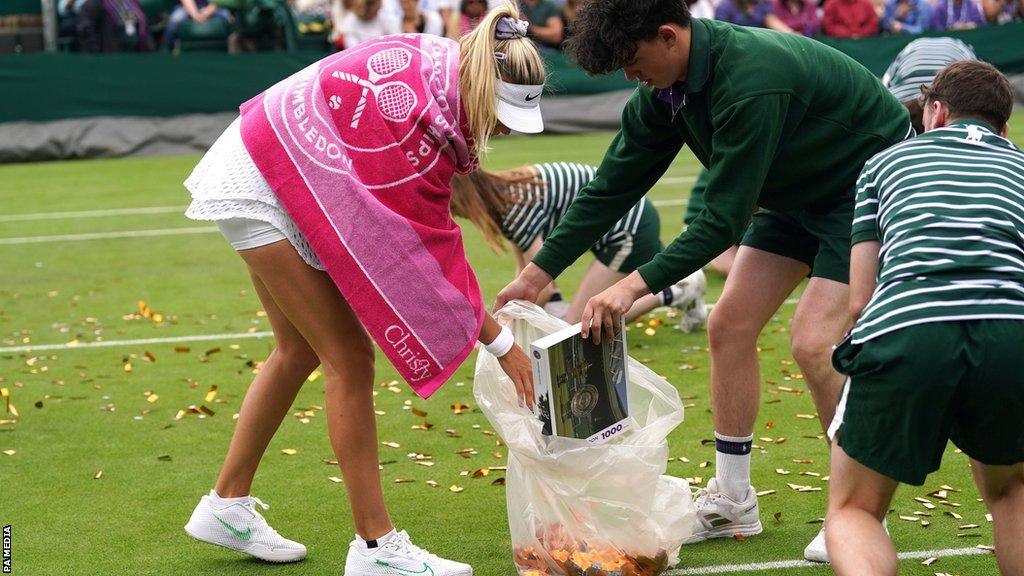 Katie Boulter helps clean up after the second protest on Court 18