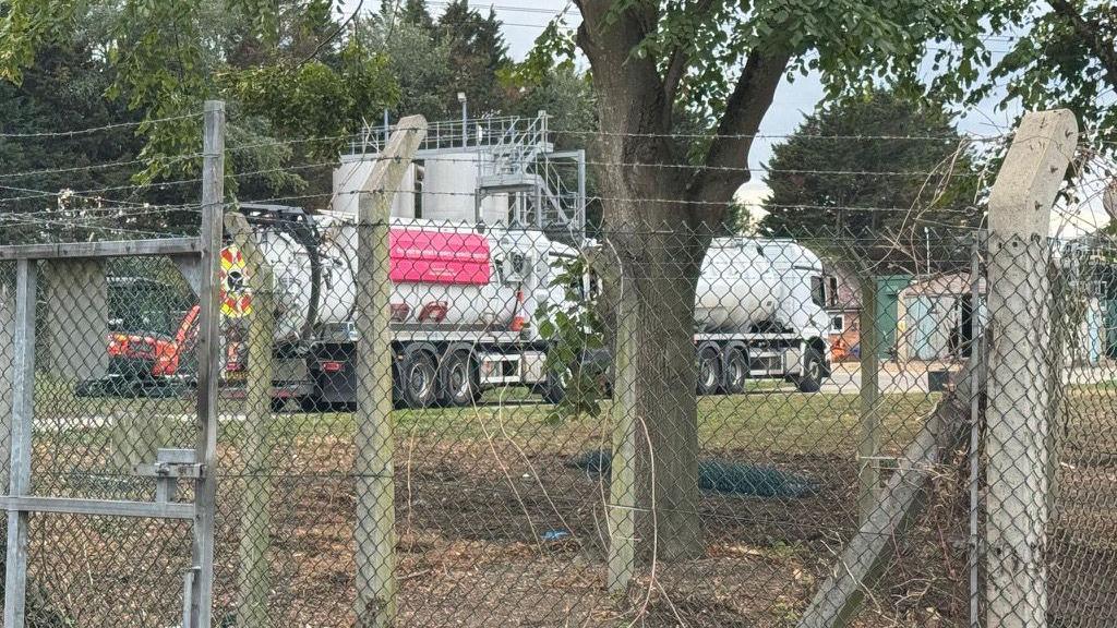 A tanker truck on site of Wheatley Sewage Treatment Works. It can be seen behind a metal fencing.