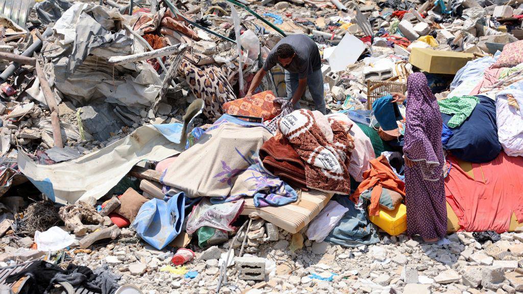 A Palestinian man and woman retrieve their bedding and clothes from the rubble of a destroyed building in Jabalia refugee camp, in the northern Gaza Strip (3 June 2024)