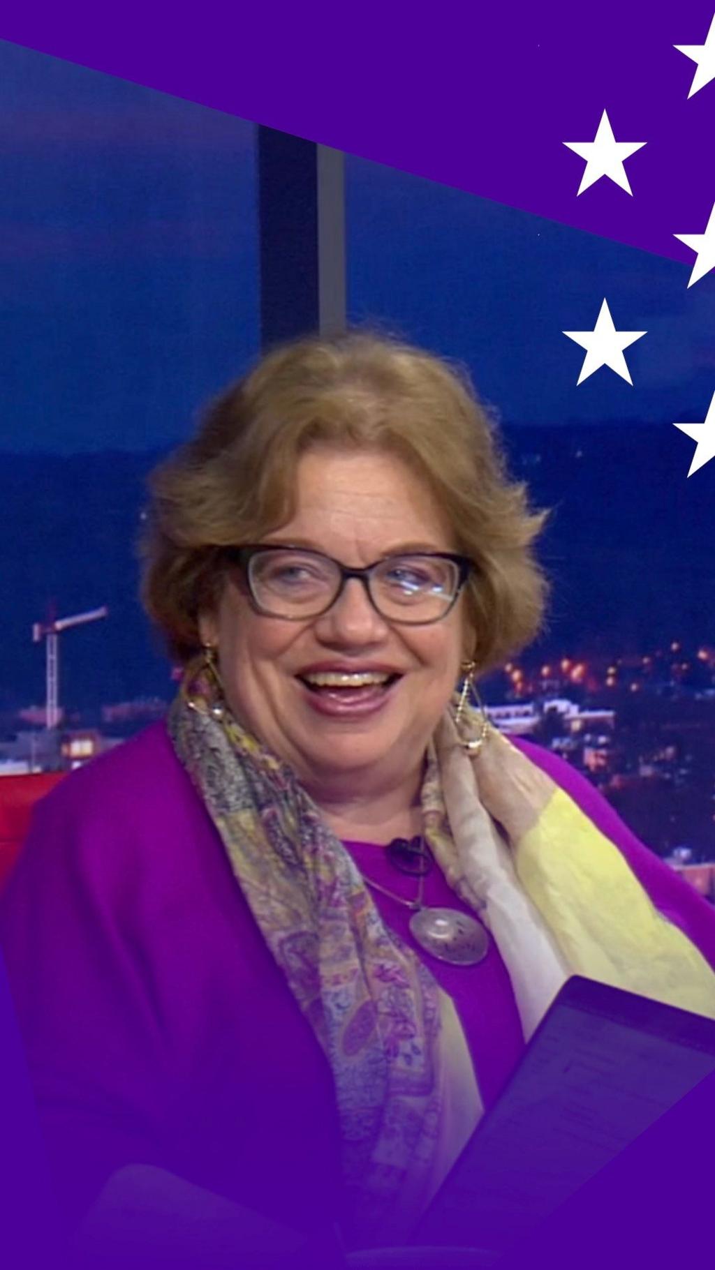 A woman with brown hair and glasses smiles