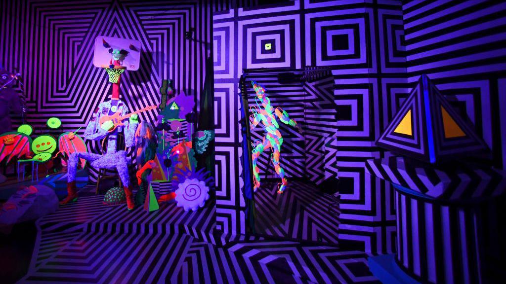 An art installation with purple and neon green, pink and yellow colours and abstract shapes