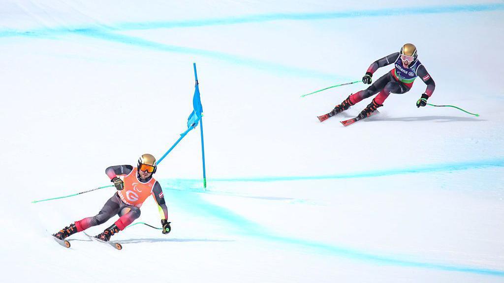 Johannes Aigner skis behind guide Nico Haberl