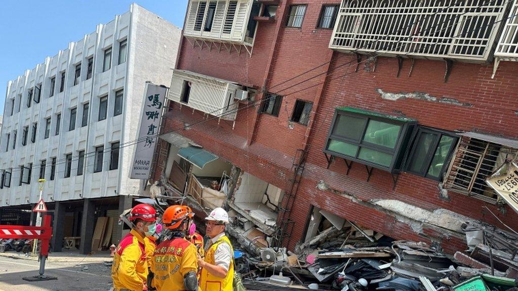 Officials standing next to a damaged building