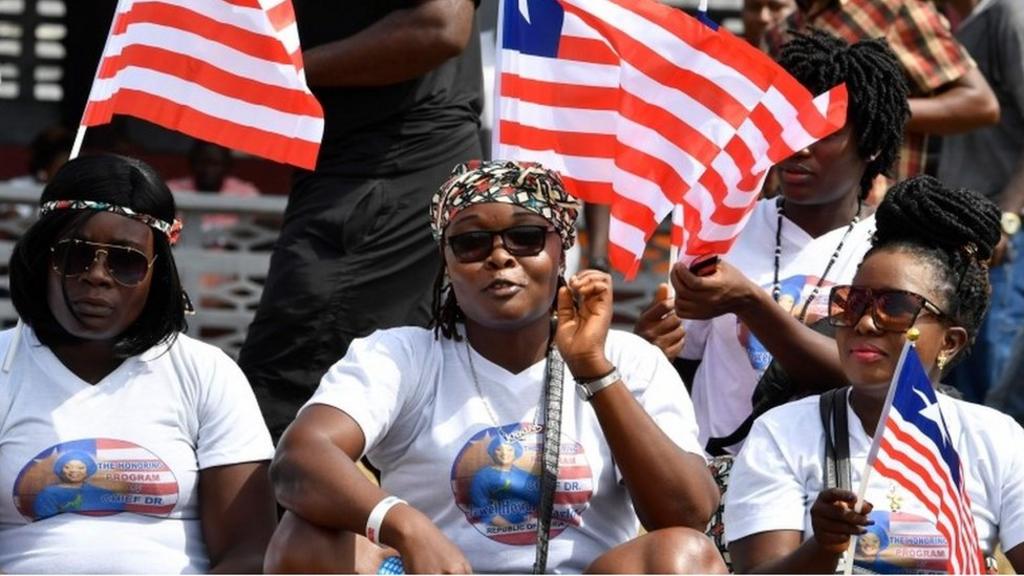 People hold Libearian flags as they attend a friendly football match between Weah All Stars, the team of Liberia's president-elect, and Armed Forces of Liberia team on January 20, 2018, in Monrovia, two days ahead of the presidential inauguration