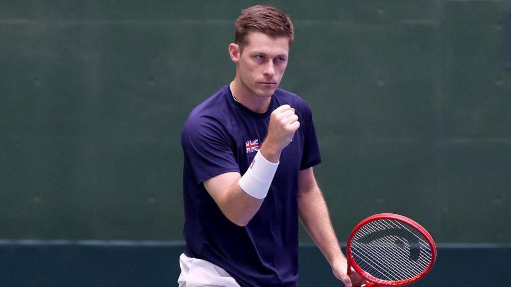 Neal Skupski raises his first in celebration after winning a point for Great Britain in the 2025 Davis Cup match against Japan.