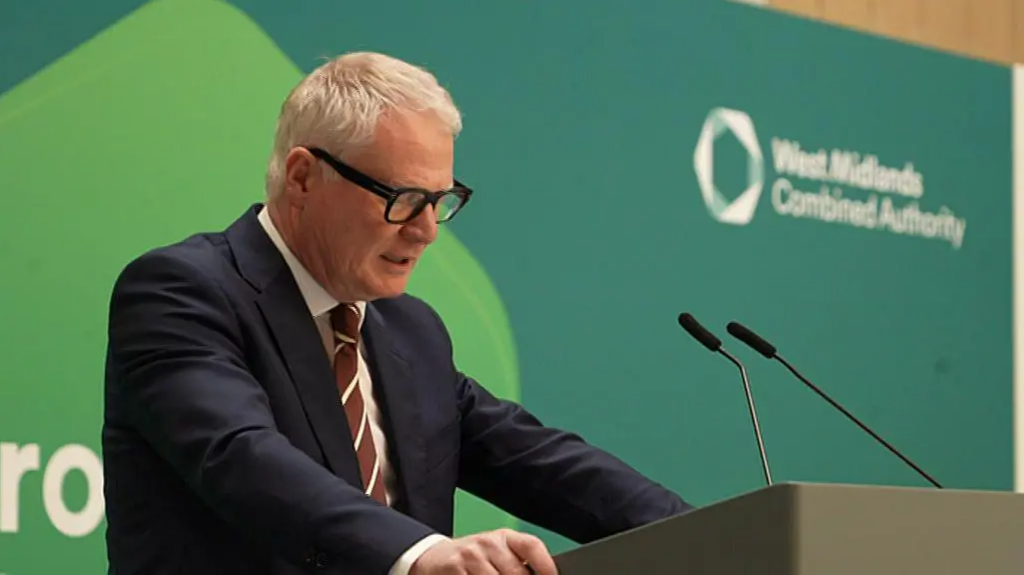 West Midlands Mayor Richard Parker talking at a podium with a green background