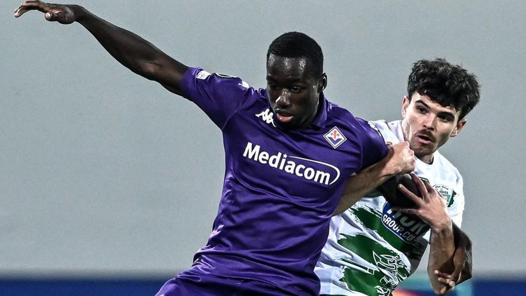 Michael Kayode of Fiorentina competes for the ball with Ben Clark of The New Saints