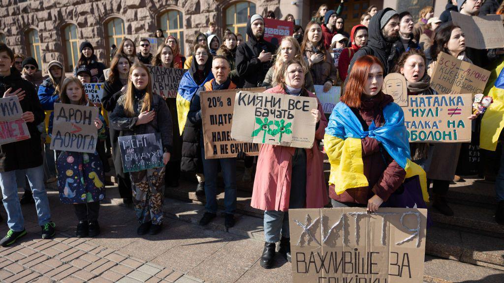 Protesters hold placards expressing their opinion during a rally denouncing corruption and calling for better funding of the Ukrainian armed forces in central Kyiv