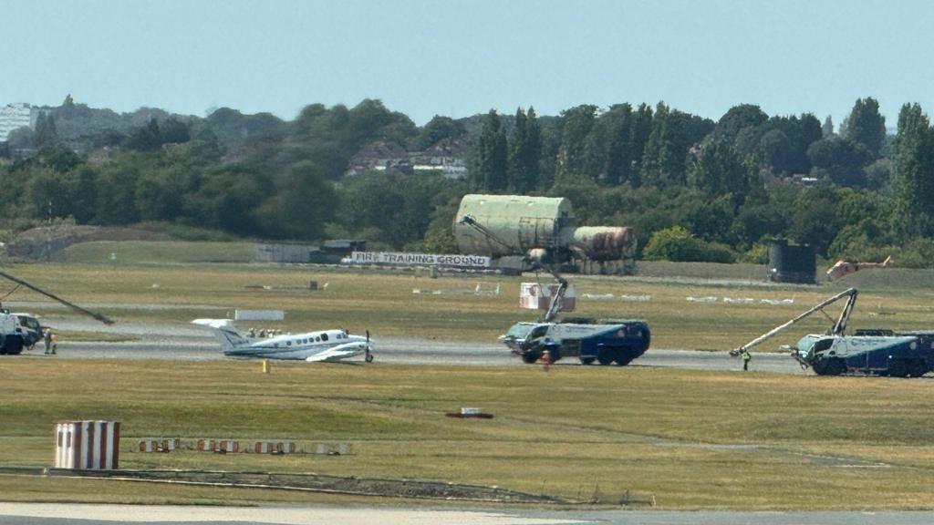 A small white plane sits on the runway
