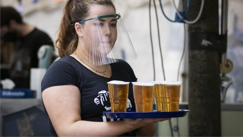 A member of staff serves drinks in the beer garden at the Bier Halle, Glasgow, as outdoor areas reopen to the public for the first time