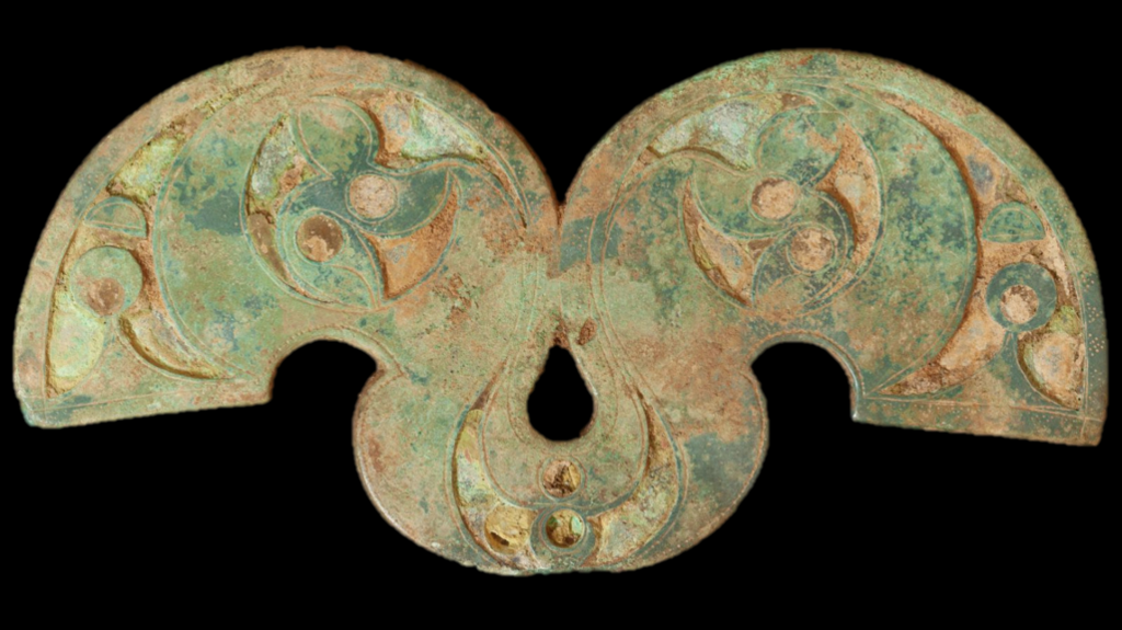 A turquoise- and copper-coloured brooch with some ornamentation.