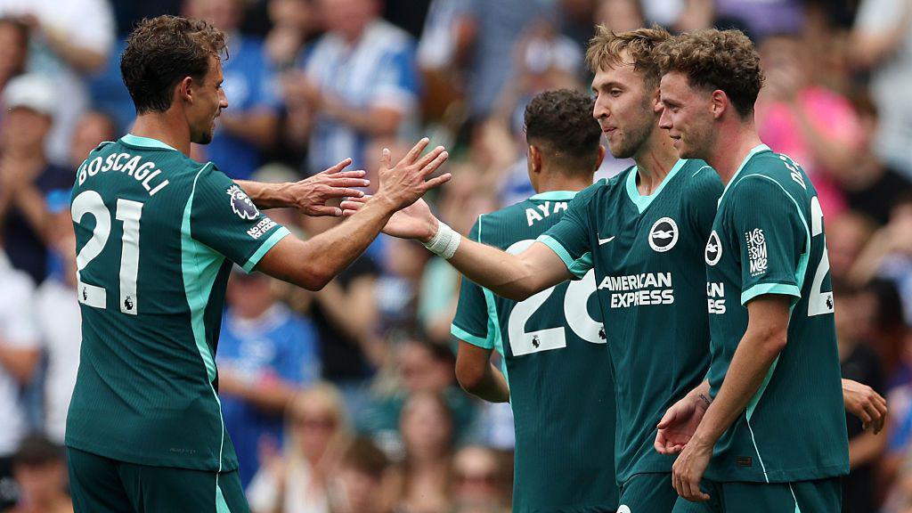 Jack Hinshelwood of Brighton and Hove Albion (C) celebrates scoring his team’s first goal with teammates Maxim De Cuyper (R) and Olivier Boscagli (L) 