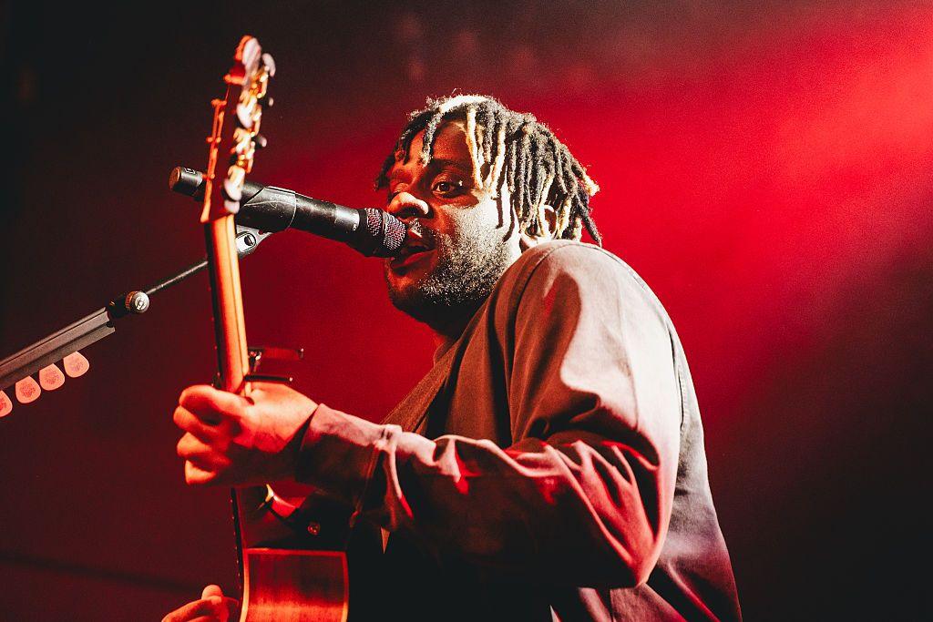 Singer Myles Smith holding guitar and singing into the microphone.