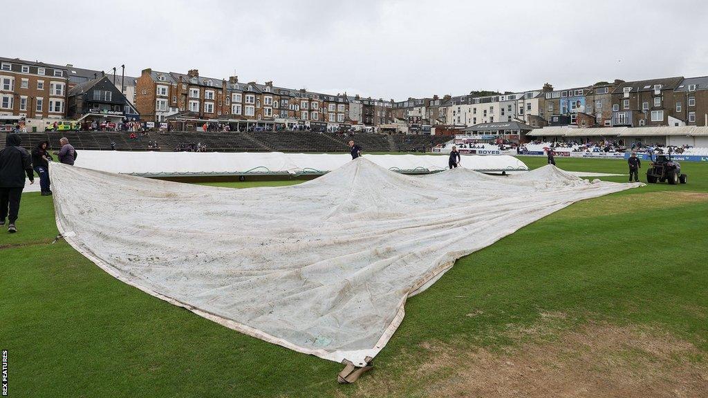 Groundstaff pull on the covers at North Marine Road