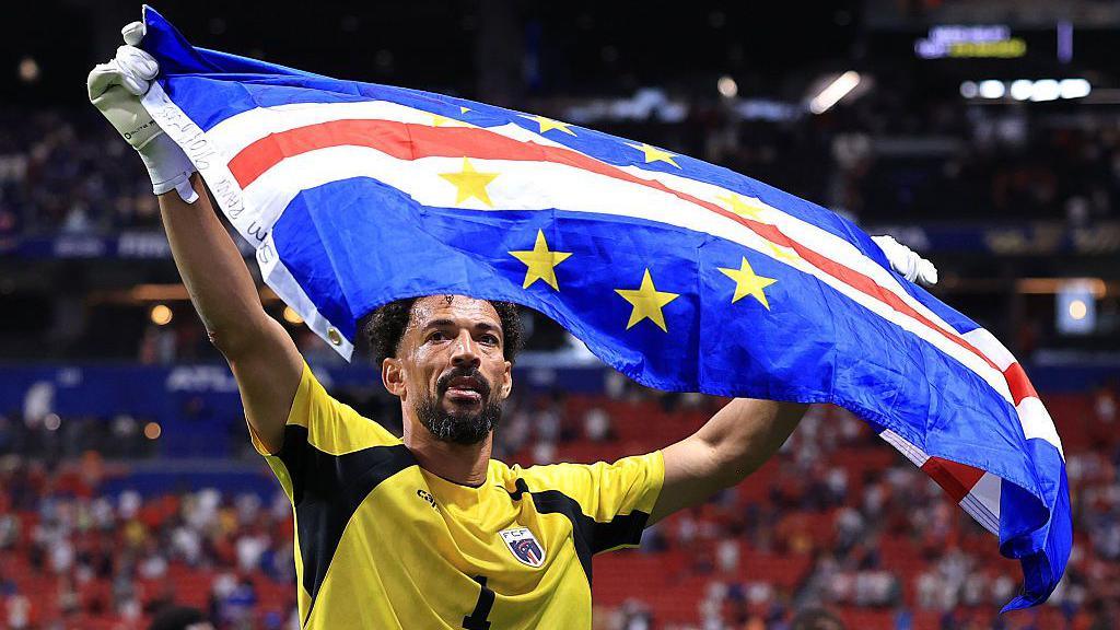 Vozinha holds a Cape Verde flag
