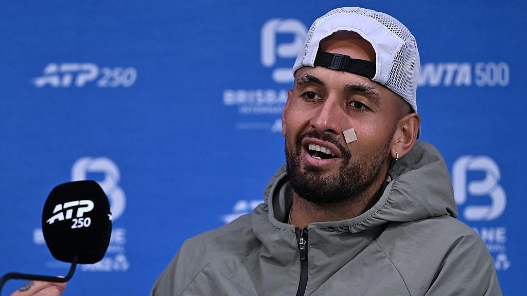 Nick Kyrgios sits in front of a microphone and answers questions in a news conference in Brisbane 