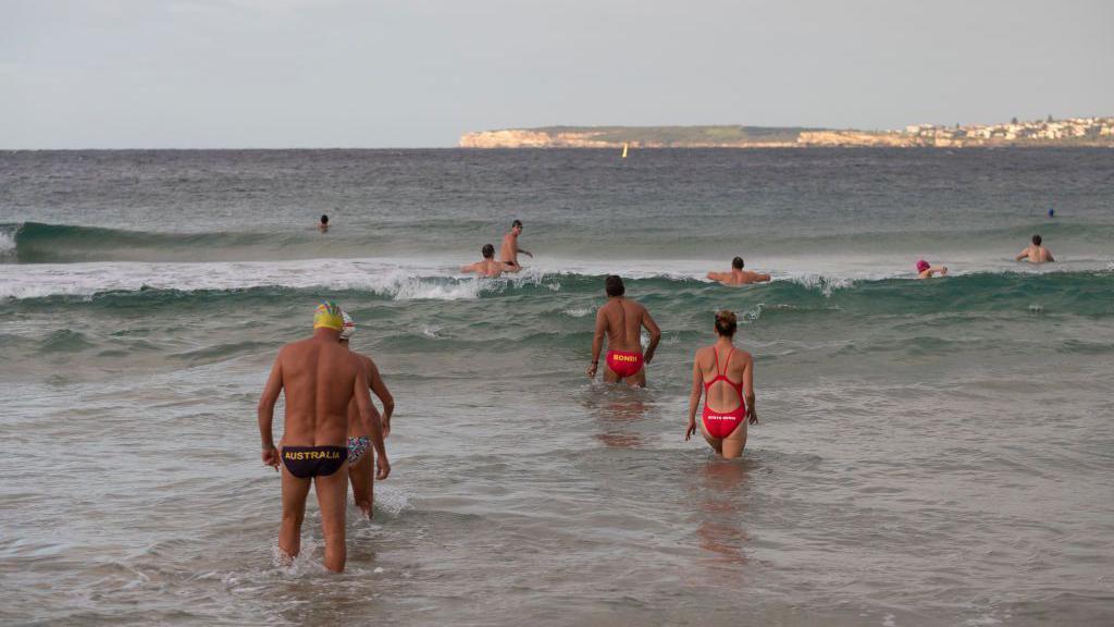 Swimmers walking into the water at Bondi beach 