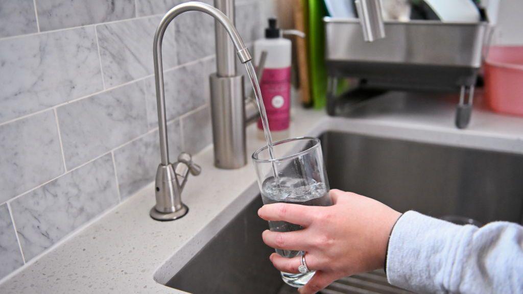 person filling up water glass