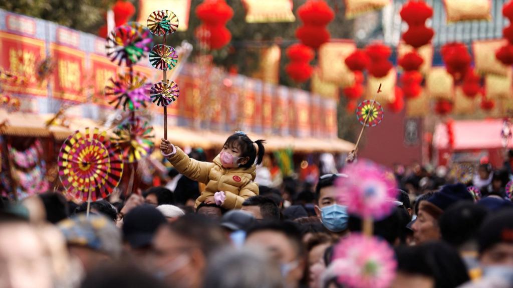 A child sits on someone's shoulders as people gather at a temple fair in Beijing, China