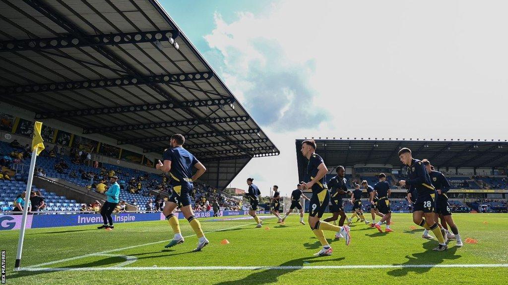 Oxford United players warming up at the Kassam Stadium ahead of a League One match.