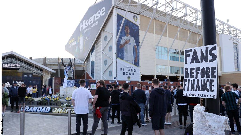 A banner reads 'fans before finance' outside Elland Road during protests against the European Super League