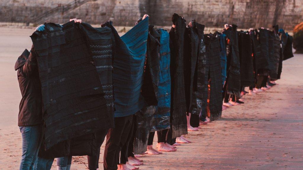 Women standing in line hold their banners against the sunrise.