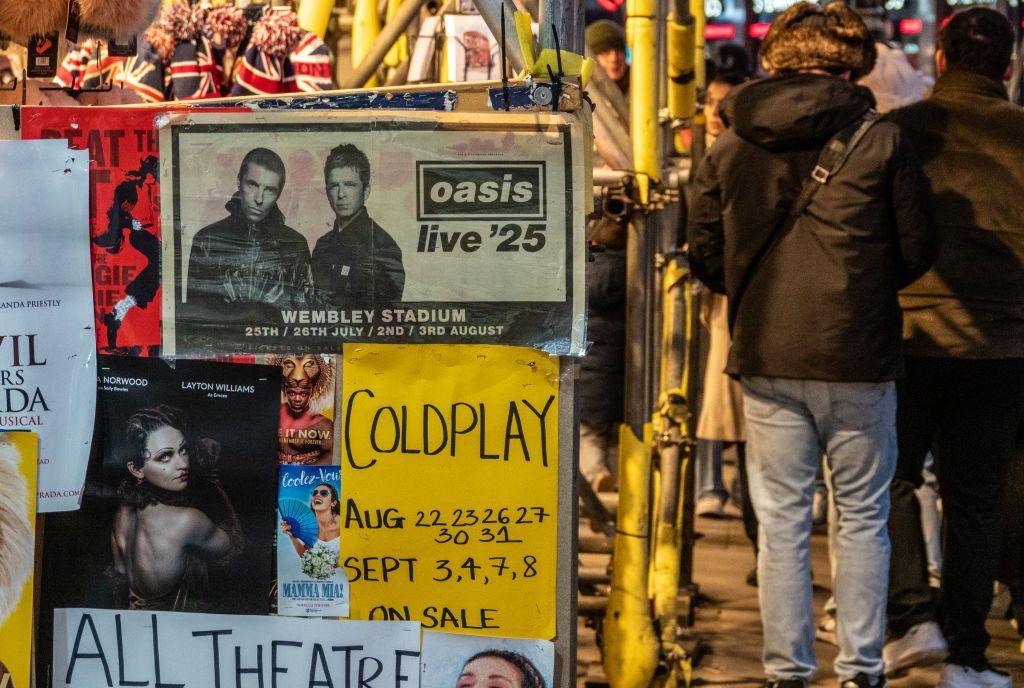 People pass a poster advertising Oasis tickets for their London gigs on December 28, 2024 in London.