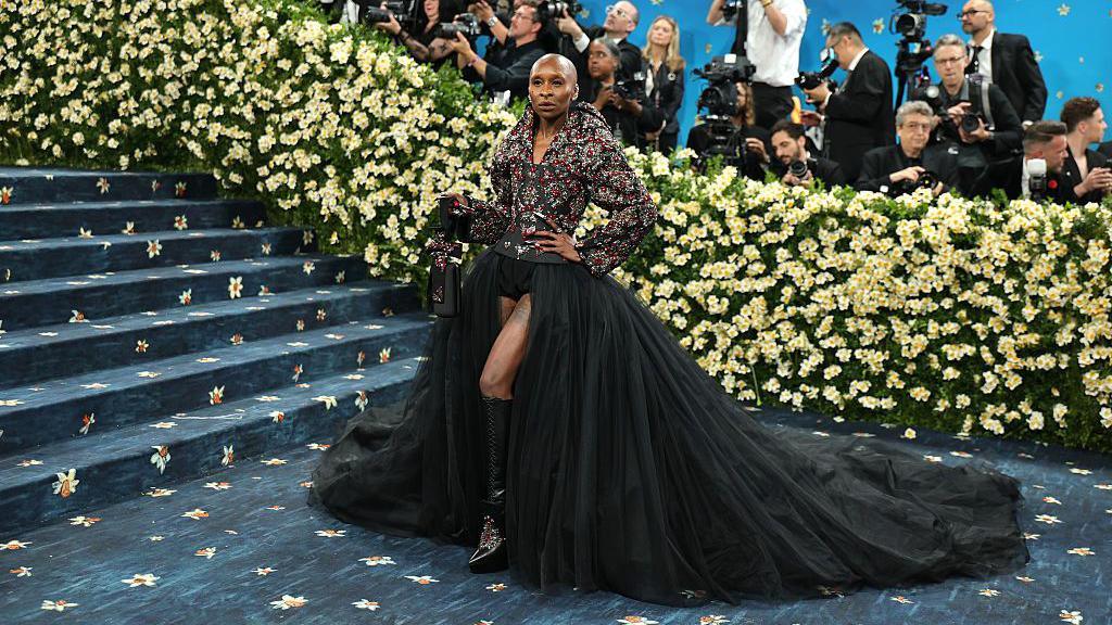 Cynthia Erivo attends the 2025 Met Gala in a black dress decorated with silver and ruby red jewels and towering heels