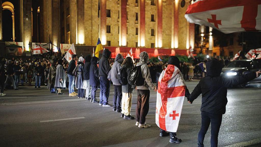 Protesters with Georgian flags attempt to block Rustaveli Avenue during a demonstration demanding the release of political prisoners and new elections