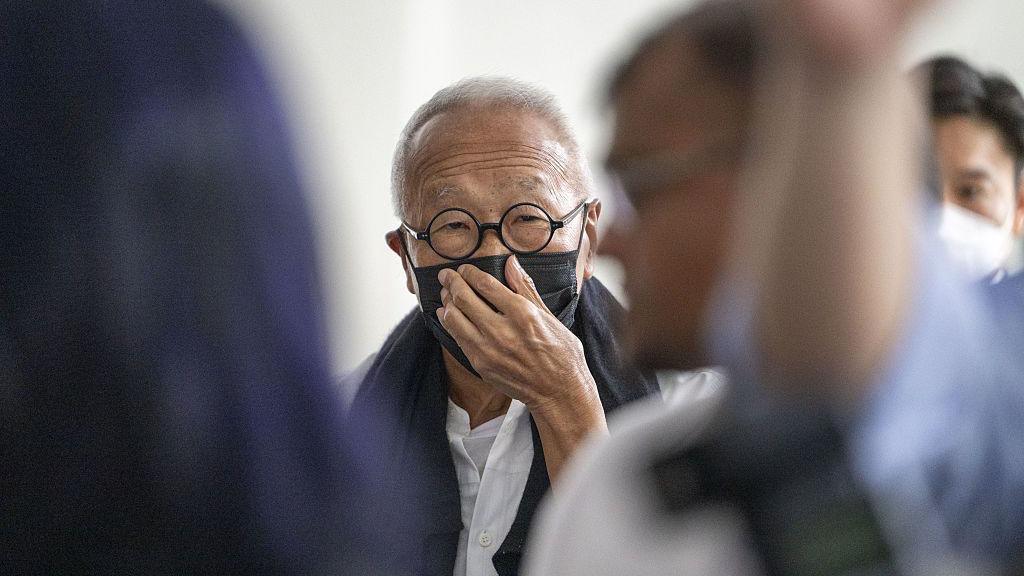 Ong Beng Seng wearing a black mask and round spectacles. He is covering his mouth with his hand.
