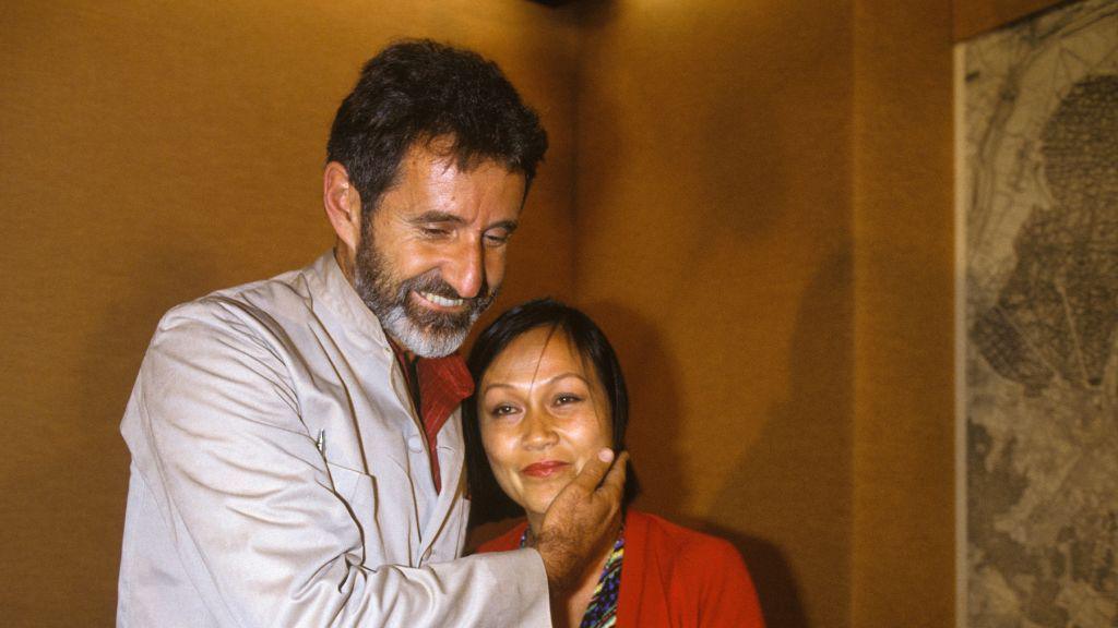 The South African poet Breyten Breytenbach, wearing a grey shirt, embraces his wife, who is wearing a red jumper.