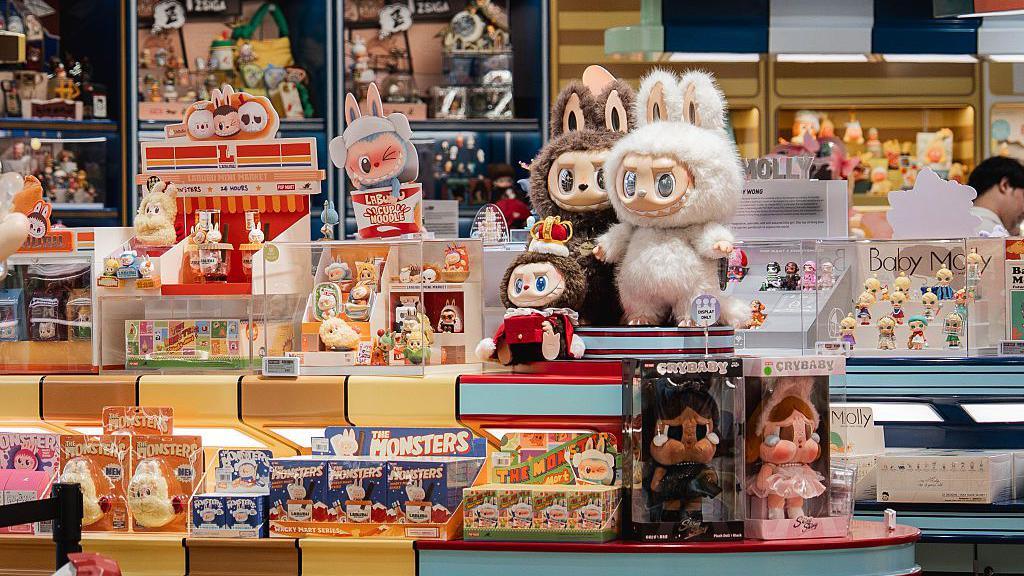 A close-up display of an array of Labubu figurines and plush toys - some inside their packaging; some outside.