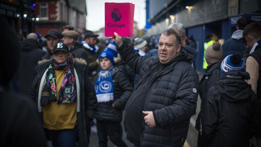 A supporter distributing posters on Goodison Road