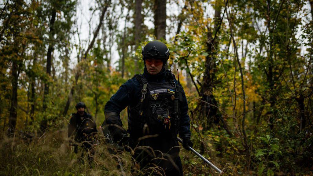 Members of the de-mining team comprised of firefighters from Kramatorsk search for an unexploded ordinance in Sloviansk, Donetsk Region, Ukraine on October 17, 2024. The team uses metal detectors to search for mines and plastic explosives to destroy unexploded ordinance like mortars, shells and rocket-propelled grenades.