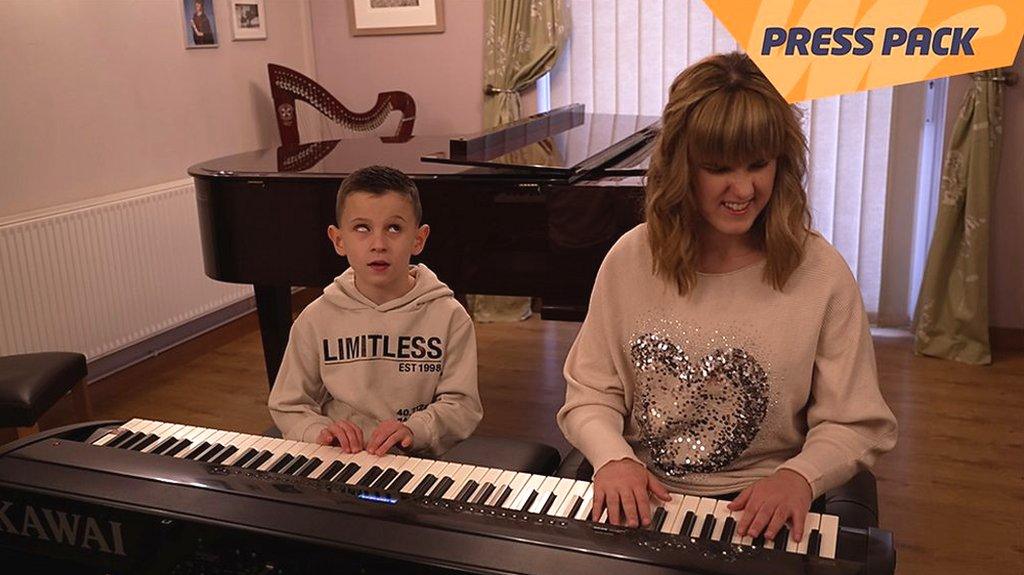 Alfie sits on the left, playing piano with rachel, on the right