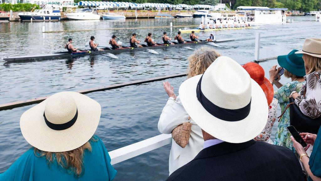 People watch rowers on the river