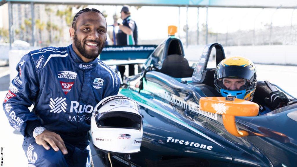 AJ McKee posing for a photo next to a sports car