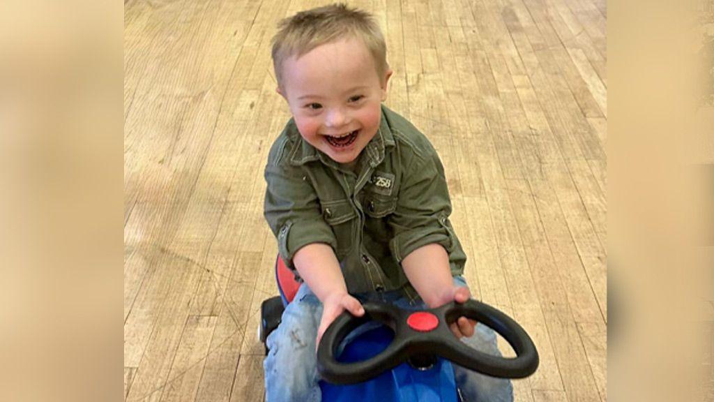 Ethan playing on a ride-along toy with big smile on his face